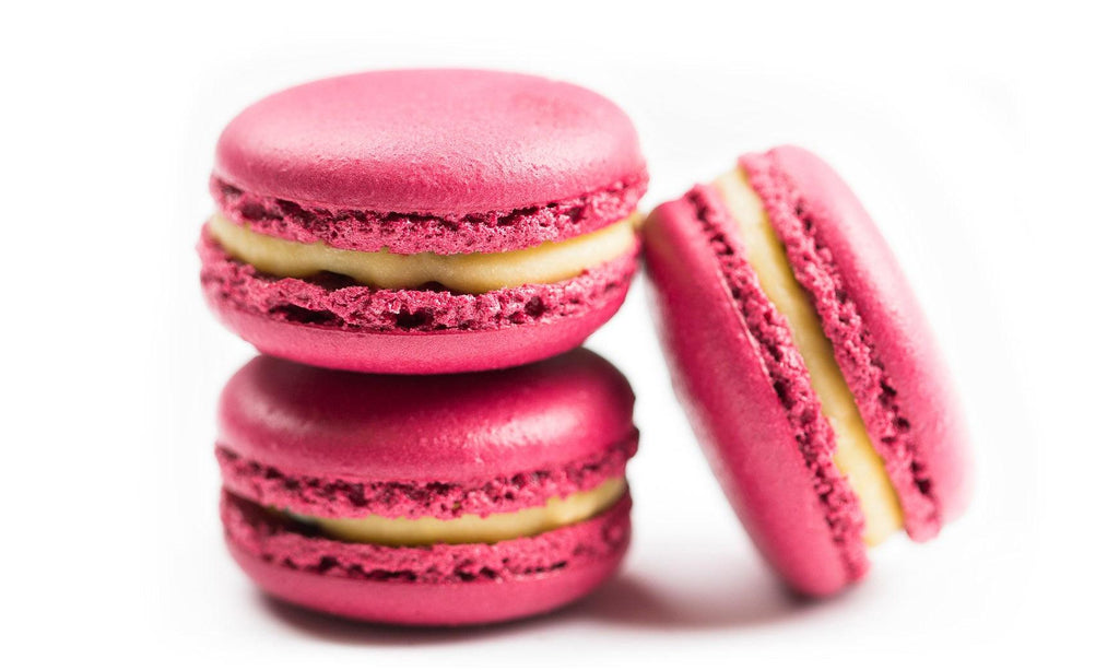 12 pack of Beetroot Passionfruit Macarons which are Two purple mounds of almond meringue sandwiched, between tart passionfruit buttercream 
