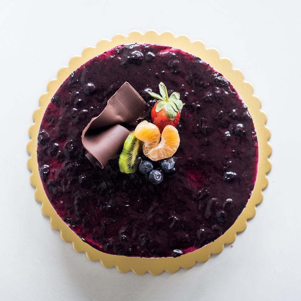Pasticceria Papas Bluberry Cheese Cake decorated with chocolate swirl and fruit